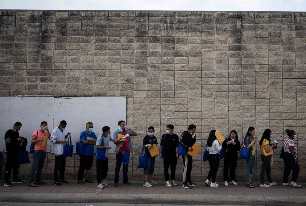 PHOTO: TOPSHOT - Migrants line up outside a processing center on May 11, 2023 in Brownsville, Texas. The US on May 11, 2023, will officially end its 40-month Covid-19 emergency, also discarding the Title 42 law.