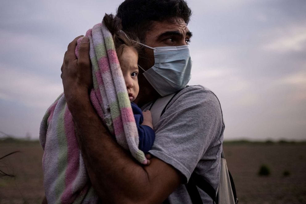 Francisco, 34, an asylum seeking migrant from Honduras, cradles his nine-month-old daughter Megan as they await for transport to a processing center after crossing the Rio Grande river into the US from Mexico on a raft in La Joya, Texas, March 25, 2021.