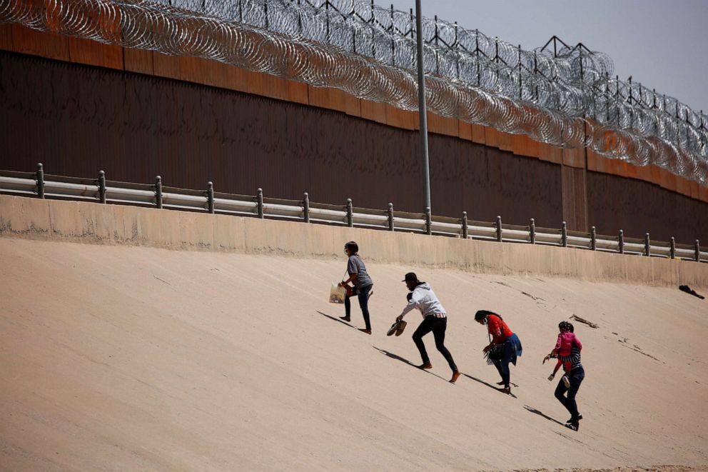 PHOTO: Asylum-seeking migrants walk near the border wall after crossing the Rio Bravo, in El Paso, Texas, as seen from Ciudad Juarez, Mexico, April 6, 2022.