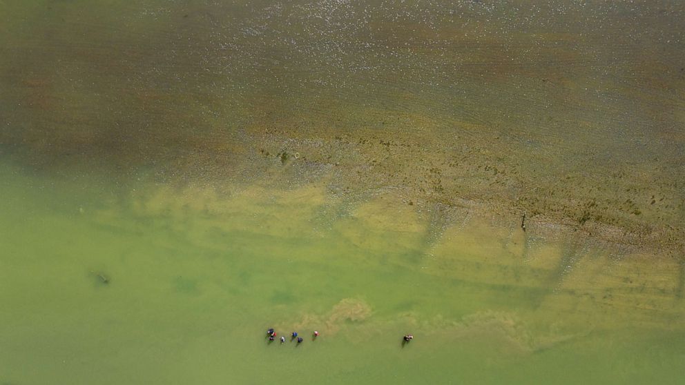 PHOTO: In an aerial view, migrants seeking asylum walk alongside buoy barriers in an attempt to cross the Rio Grande river into the United States in Eagle Pass, Texas, on July 18, 2023.