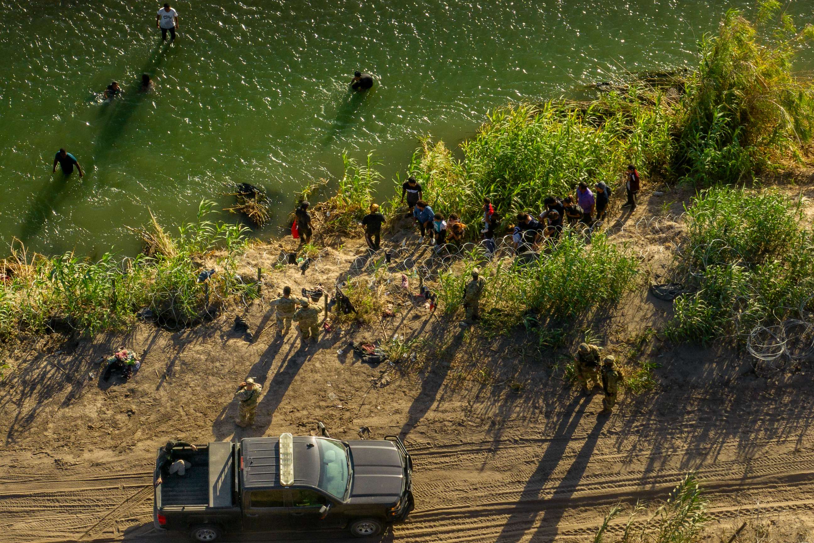 PHOTO: In an aerial view, migrants seeking asylum receive instructions from law enforcement officers in Eagle Pass, Texas, after crossing the Rio Grande river into the United States on July 18, 2023.
