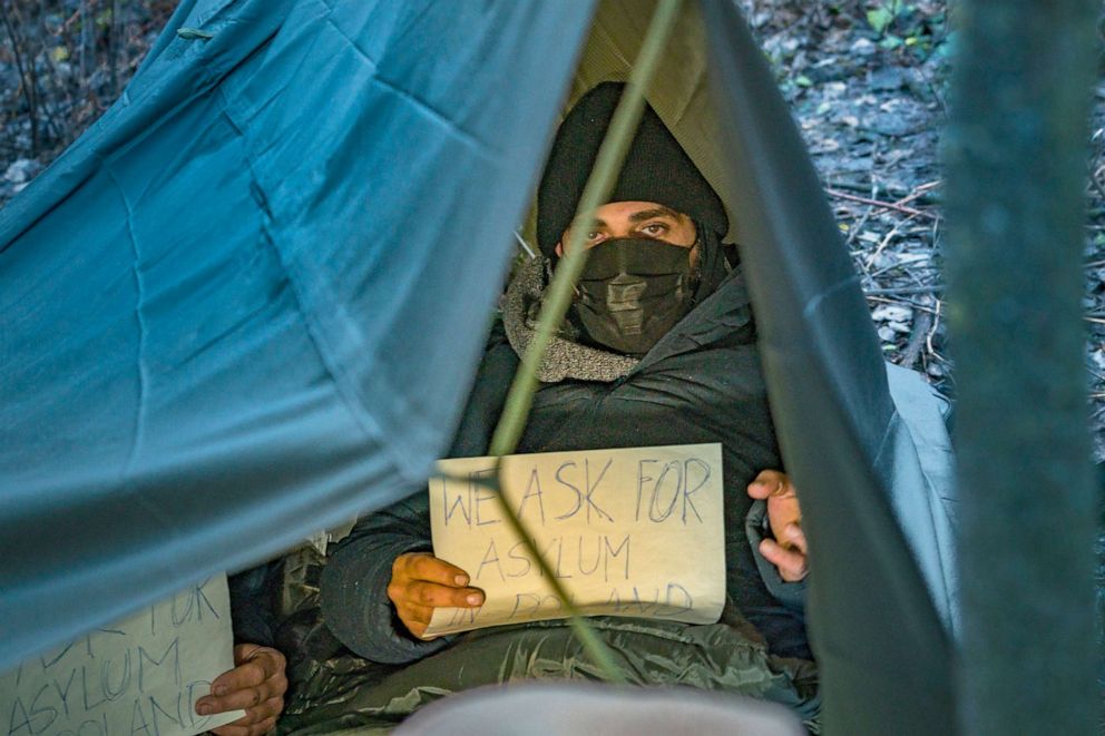 PHOTO: A Syrian refugee holds a sign asking for asylum while taking shelter in a tent in the forests of Poland, Nov. 26, 2021.