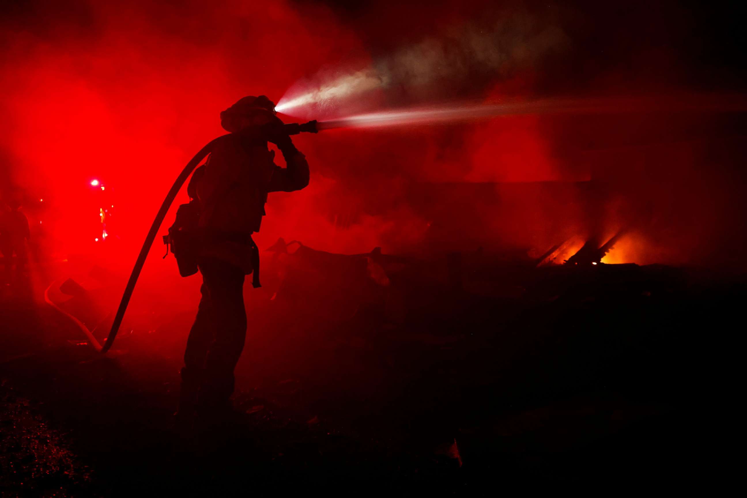 PHOTO: Fire fighter Andrew Alves hoses down hotspots in homes that were burnt as the Mill Fire burns near Weed, Calif., Sept. 2, 2022.