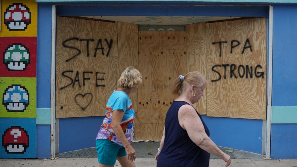 PHOTO: People walk past boarded up storefronts in Tampa ahead of Hurricane Milton's expected landfall in the middle of this week, Oct. 8, 2024, in Fla. 