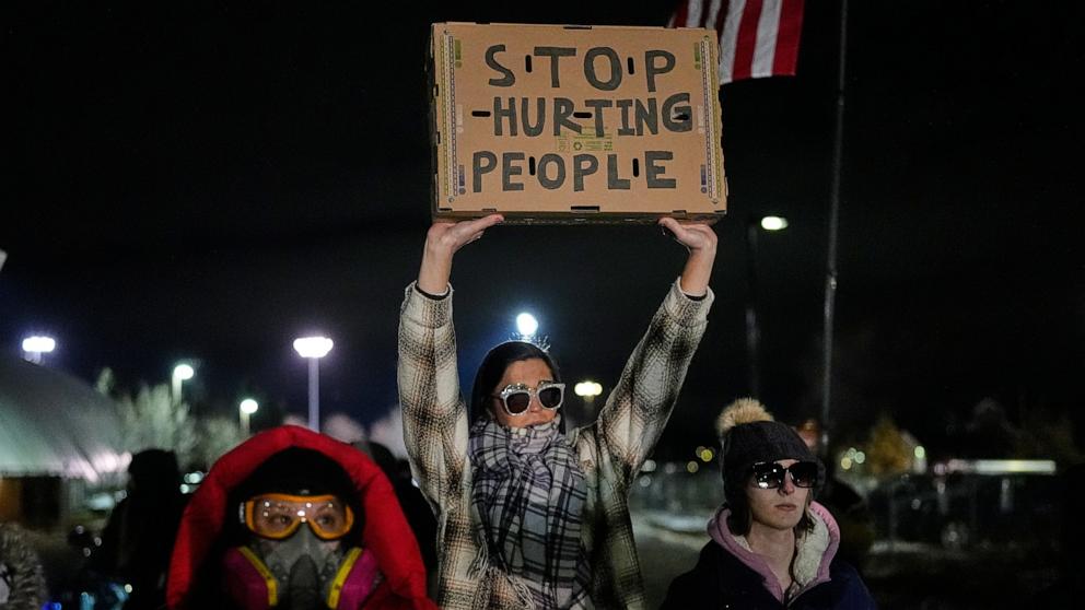 PHOTO: A woman holds up a sign as federal immigration officers confront protesters outside Bishop Henry Whipple Federal Building, Jan. 15, 2026, in Minneapolis. 