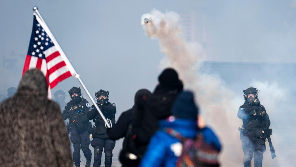 PHOTO: A Minneapolis Police officer throws a can of tear gas at people gathered on Nicollet Avenue after a fatal shooting by federal agents, January 24, 2026 in Minneapolis, Minnesota. 