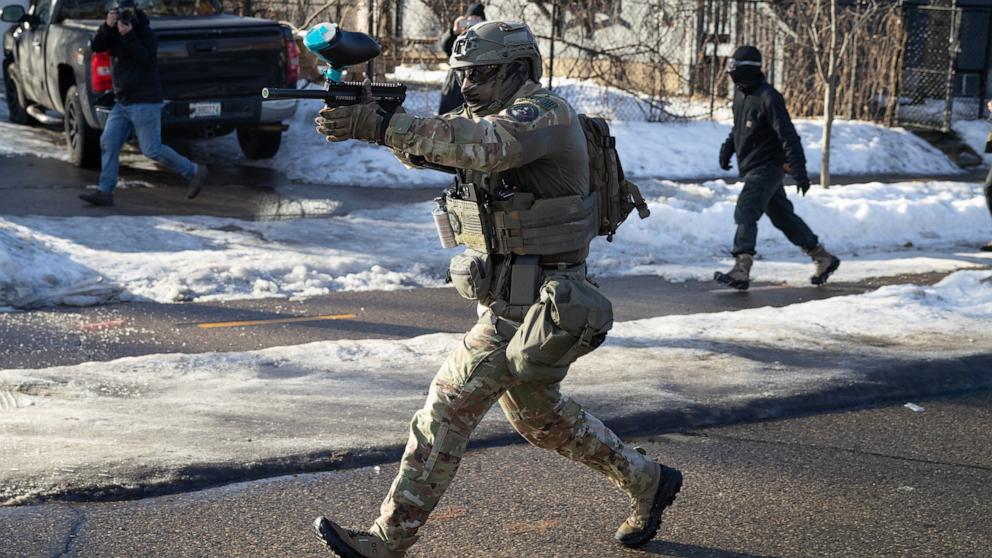 PHOTO: A federal immigration agent fires pepper while running down the street during a clash with residents following a house raid, January 13, 2026 in Minneapolis, Minnesota. 