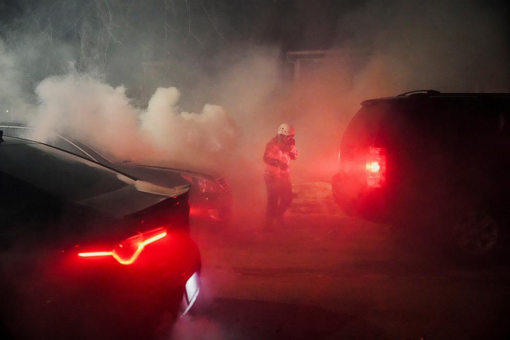 PHOTO: A protester walks amidst tear gas smoke next to vehicles, after law enforcement employed tear gas and munitions against them, in north Minneapolis, Minnesota, U.S., Jan. 14, 2026.