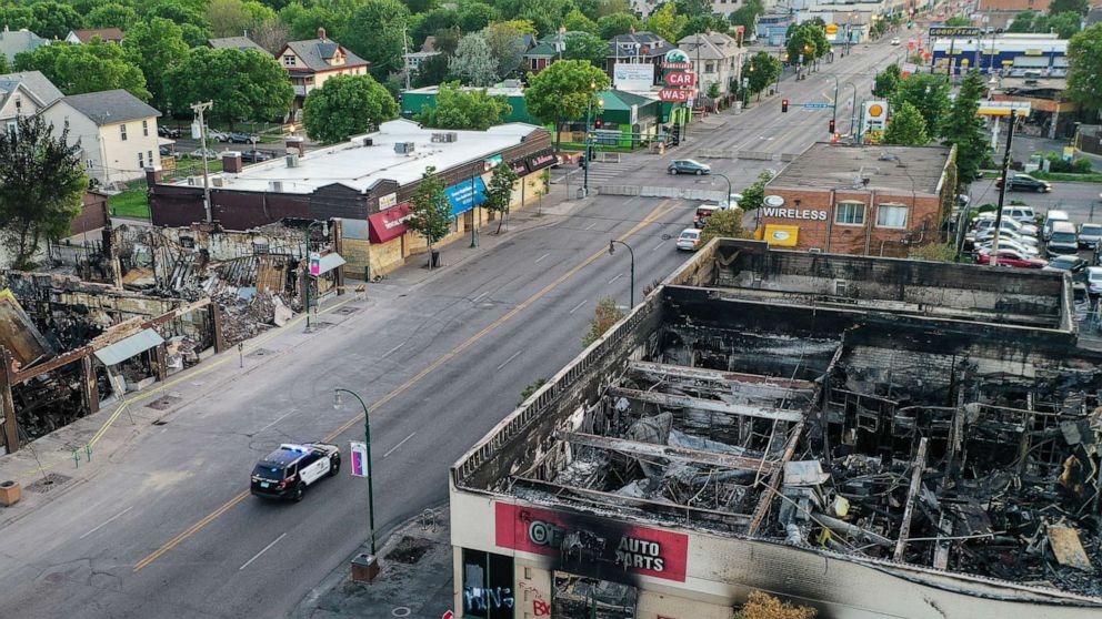 PHOTO: A police vehicle passes a building on East Lake Street that was destroyed during protests two days prior, Tuesday, June 2, 2020, in Minneapolis.