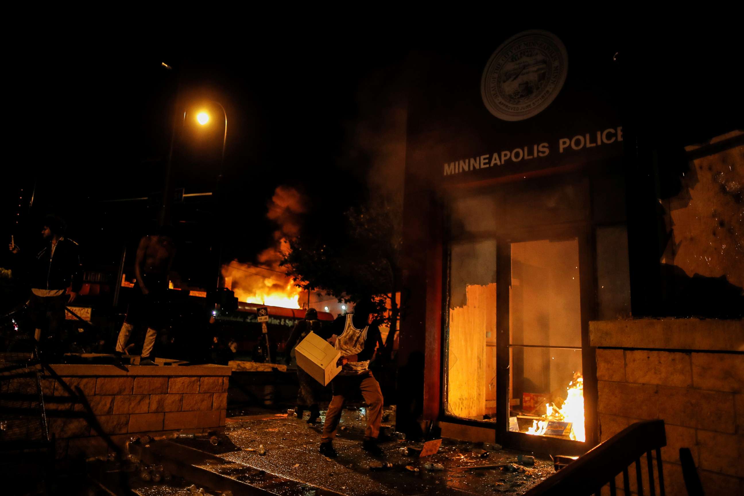 PHOTO: In this May 28, 2020, file photo, a protester sets fire to the entrance of a police station in Minneapolis, as demonstrations continue after the death of George Floyd.