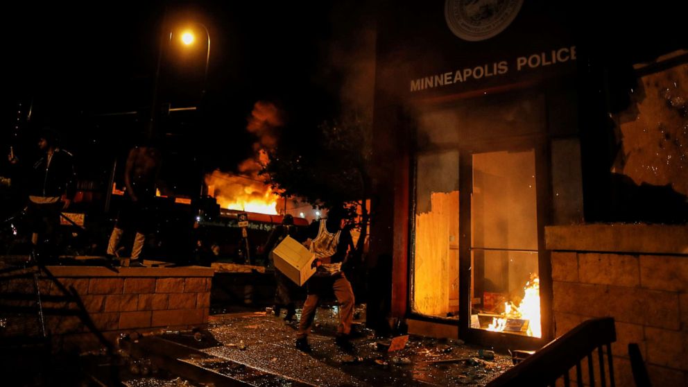 PHOTO: In this May 28, 2020, file photo, a protester sets fire to the entrance of a police station in Minneapolis, as demonstrations continue after the death of George Floyd.