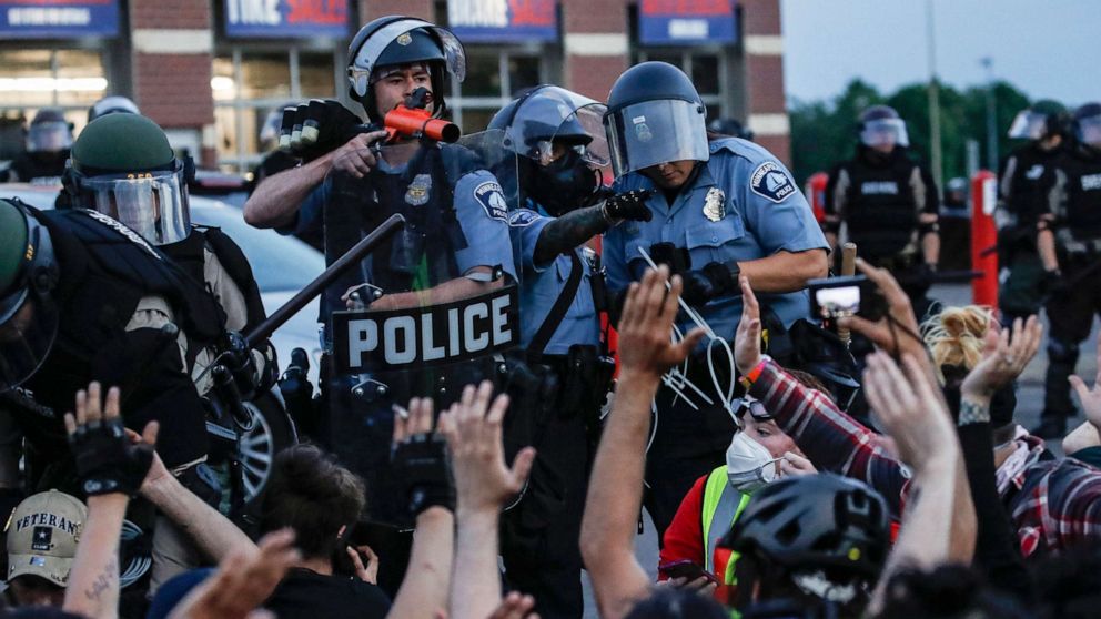 PHOTO: In this May 31, 2020, file photo, a police officer points a hand cannon at protesters who have been detained pending arrest on South Washington Street, in Minneapolis.