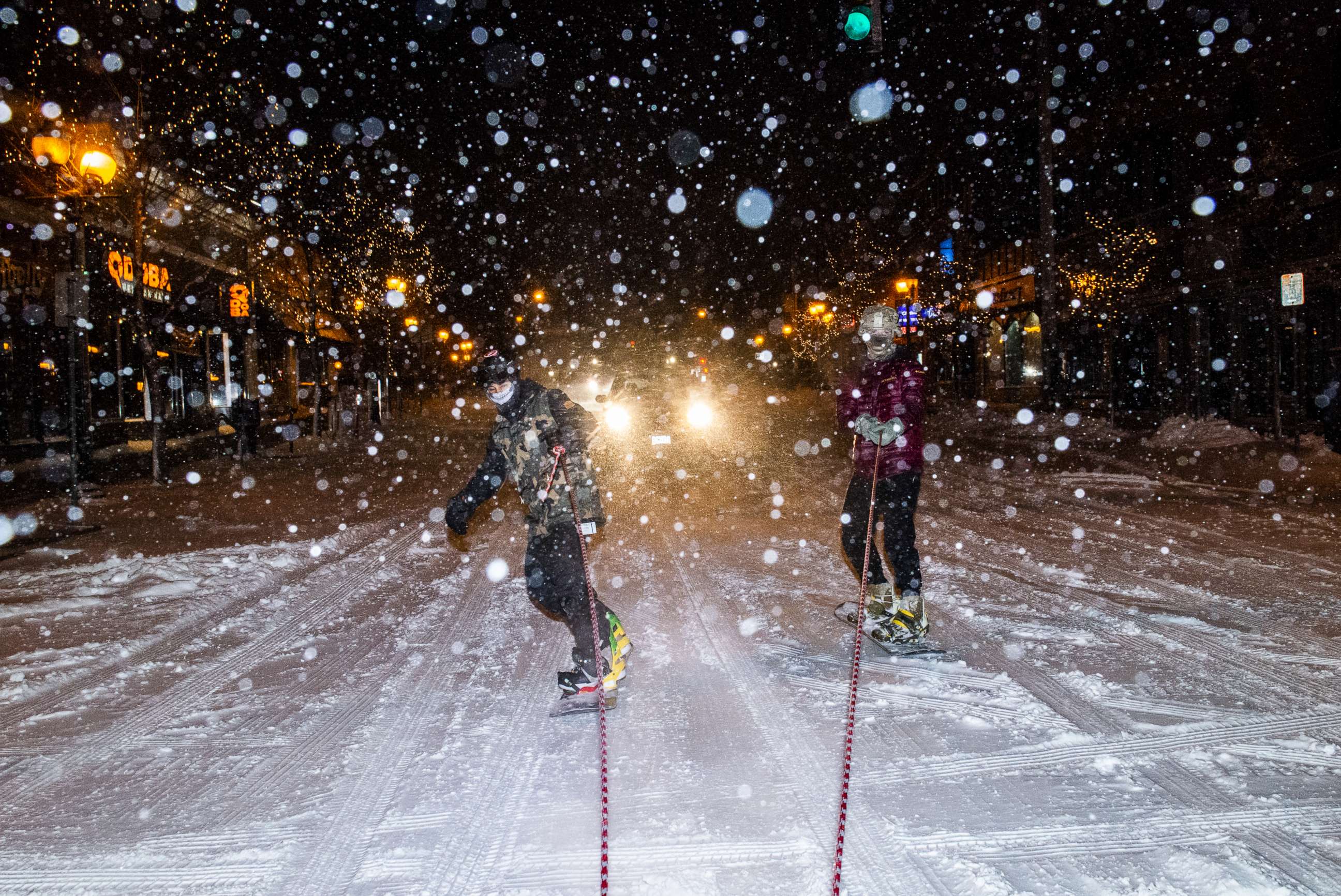 PHOTO: Snowboarders ride behind an SUV as snow continues to fall on Dec. 23, 2020, in Minneapolis.