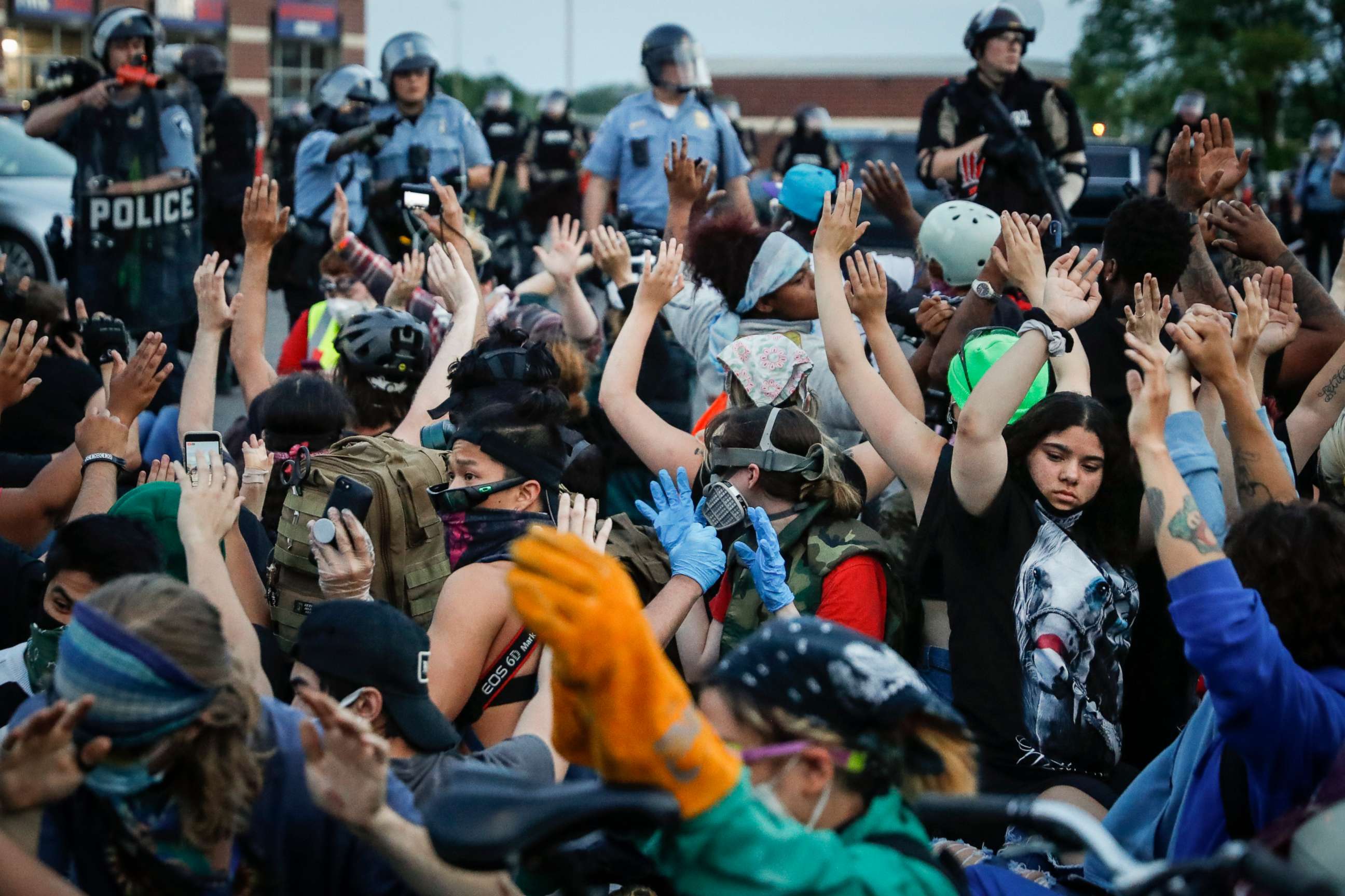 PHOTO: Protesters raise their hands on command from police as they are detained prior to arrest and processing at a gas station on South Washington Street, May 31, 2020, in Minneapolis.