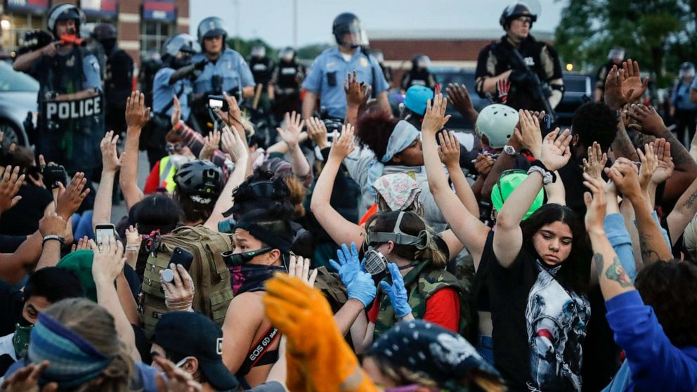 PHOTO: Protesters raise their hands on command from police as they are detained prior to arrest and processing at a gas station on South Washington Street, May 31, 2020, in Minneapolis.