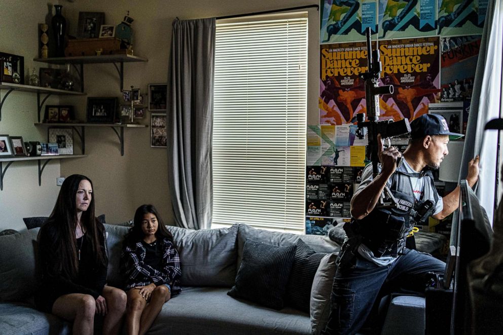 PHOTO: A member of the Minnesota Freedom Fighters looks out of a window at his home, flanked by his partner and step-daughter in Minneapolis, July 29, 2020.
