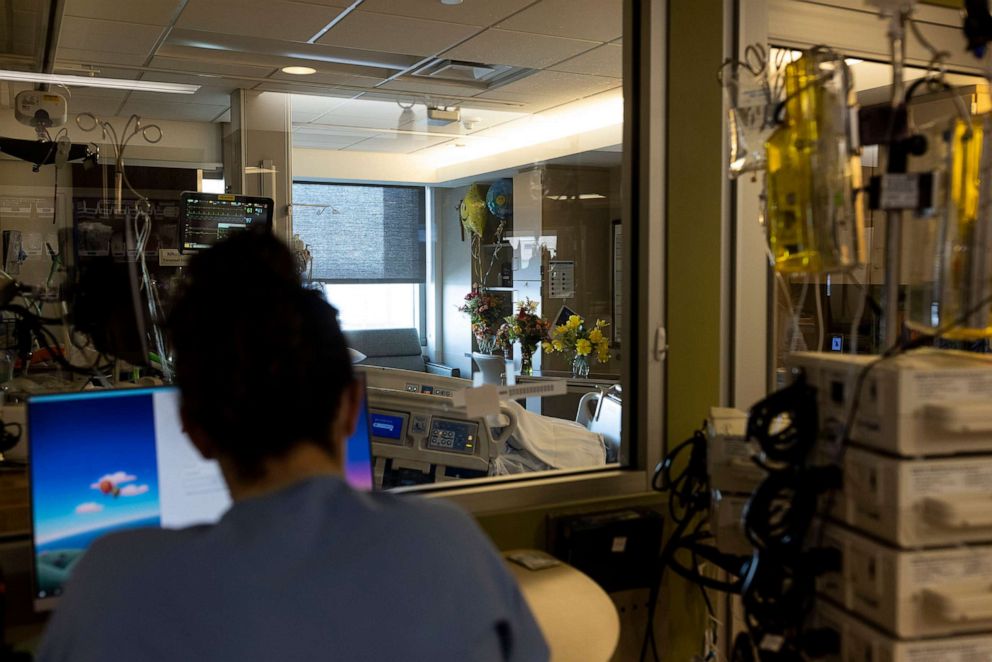 PHOTO: A nurse in the ICU looks into a covid patient's room filled with flowers and balloons at CentraCare  St. Cloud Hospital in St. Cloud, Minn., Nov. 23, 2021. 