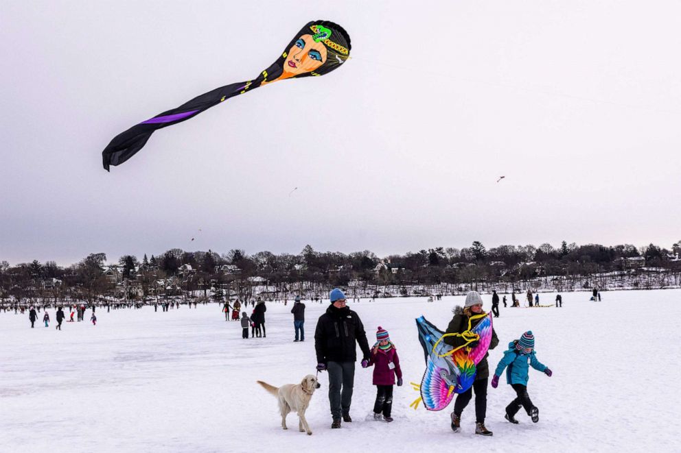 PHOTO: Attendees watch as people fly kites during the Lake Harriet Winter Kite Festival at Lake Harriet in Minneapolis, Minn. on Jan. 22, 2022.