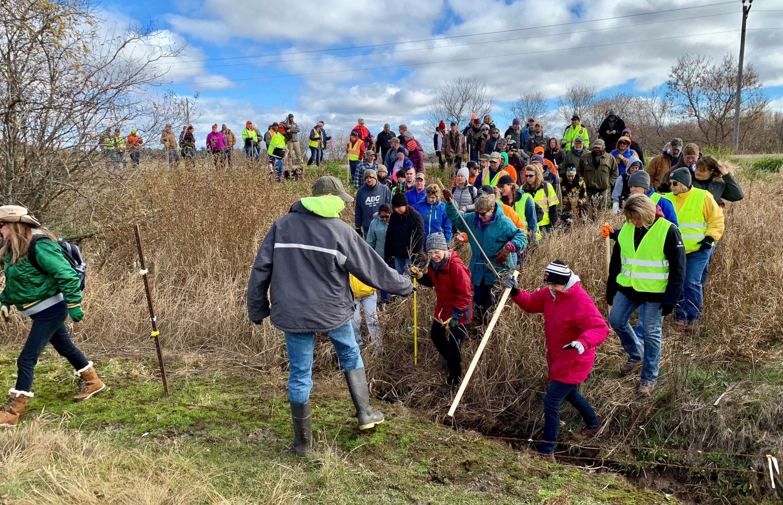 PHOTO: Volunteers cross a creek and barbed wire near Barron, Wis., Oct. 23, 2018, on their way to a ground search for 13-year-old Jayme Closs who was discovered missing Oct. 15 after her parents were found fatally shot at their home. 