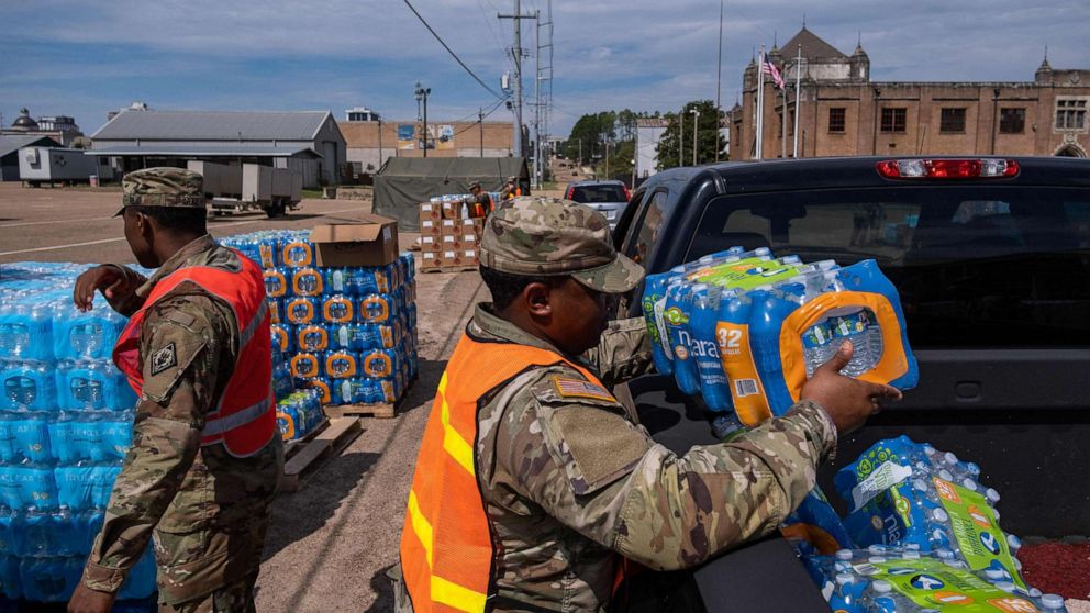 PHOTO: A member of the National Guard places a case of water in the back of a car at the State Fair Grounds in Jackson, Miss., Sept. 2, 2022. 