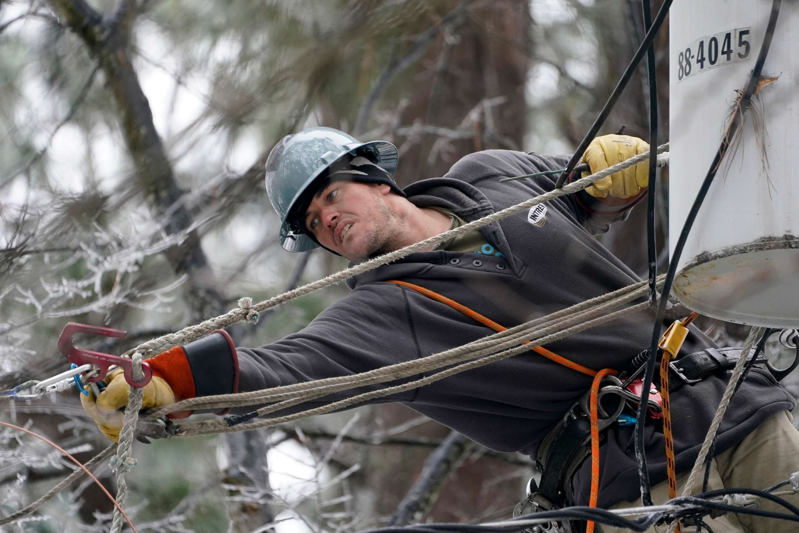PHOTO: Lineman Sean Gregory stretches for a cable as he repairs a transformer in Jackson, Miss., Feb. 18, 2021.
