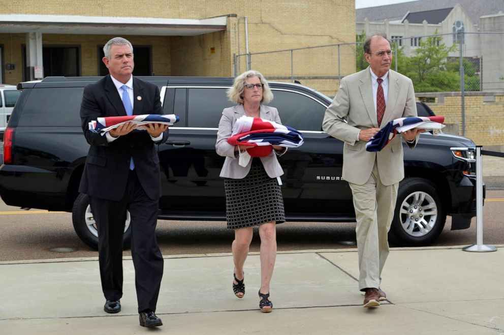 PHOTO: Mississippi House Speaker Philip Gunn, left, Department of Archives and History Director Katie Blount, and Lt. Gov. Delbert Hosemann walk to a museum with the three state flags that flew over the State Capitol in Jackson, Miss., July 1, 2020.