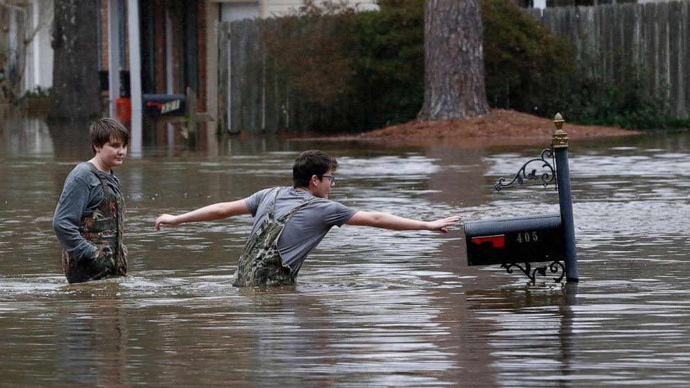 PHOTO: Blaine Henderson right, reaches to tag a mailbox as Pearl River as he and his friend Jonah Valdez play in the floodwaters of this northeast Jackson, Miss., neighborhood, Feb. 16, 2020.