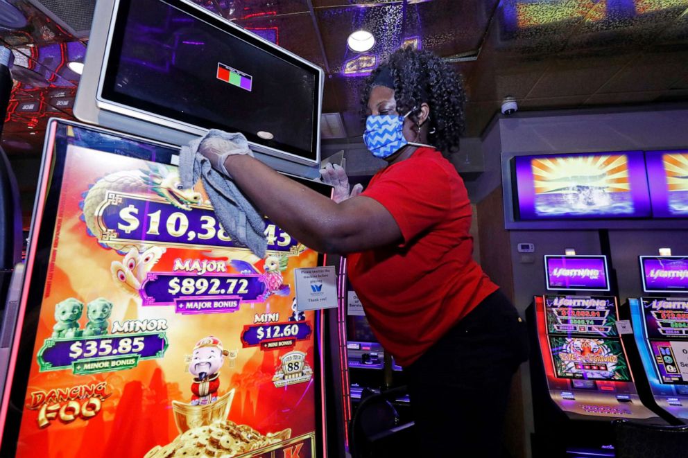 PHOTO: Annette Smith with housekeeping, sports a special WaterView Casino and Hotel mask and gloves as he cleans one of the video gaming machines throughout the Vicksburg, Miss., gaming establishment, Wednesday, May 20, 2020.