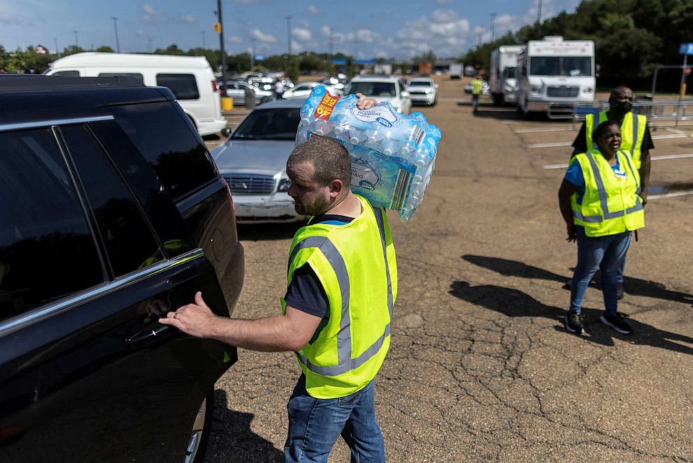 PHOTO: A volunteer helps to carry bottles of water at a water distribution site as the city of Jackson is to go without reliable drinking water indefinitely after pumps at the water treatment plant failed in Jackson, Miss., Aug. 31, 2022.