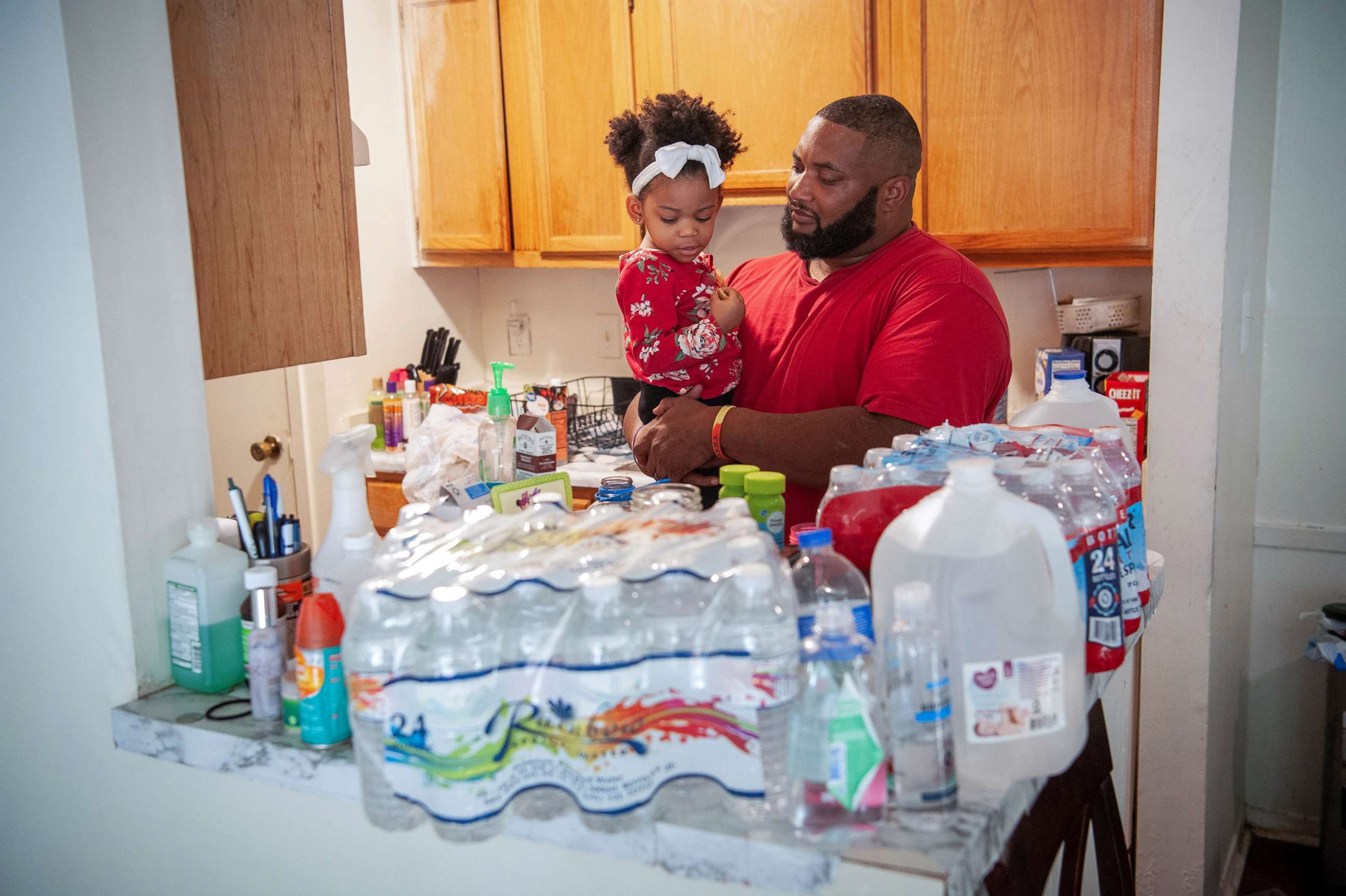PHOTO: Kevin Dudley holds his daughter, Katelyn, near to bottles of drinking water at his apartment after a recent bout of cold weather caused large numbers of water outages, some going into their third week, in Jackson, Miss., March 4, 2021.