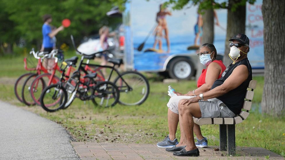 PHOTO: A man and woman sit with their masks on at Creve Coeur Lake Park on May 25, 2020 in Maryland Heights, Missouri.