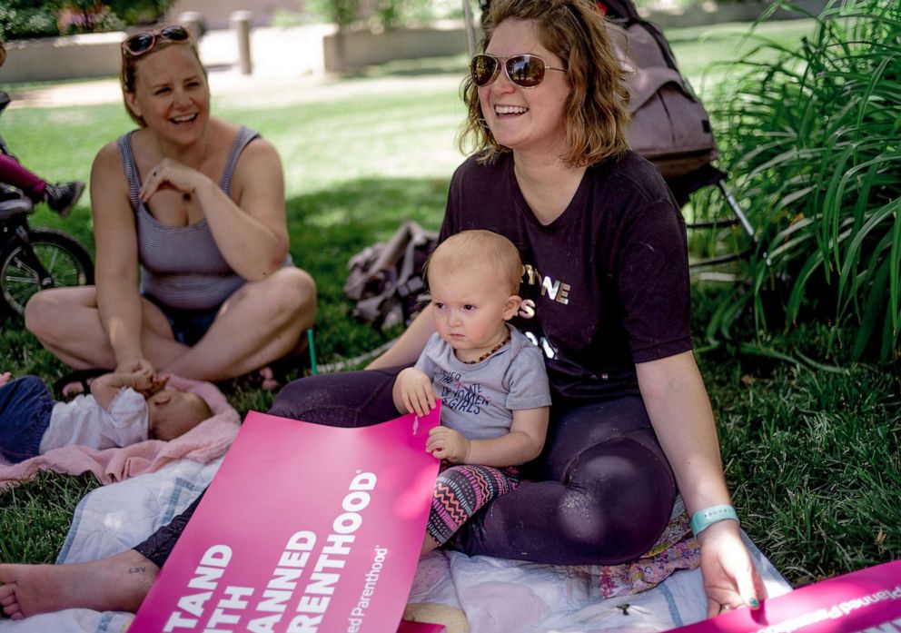 PHOTO: Jackie Gold and her daughter Juno Gold, 19 months, pass out Planned Parenthood signs before a rally to protest the closure of the last abortion clinic in Missouri on May 30, 2019, in St Louis.