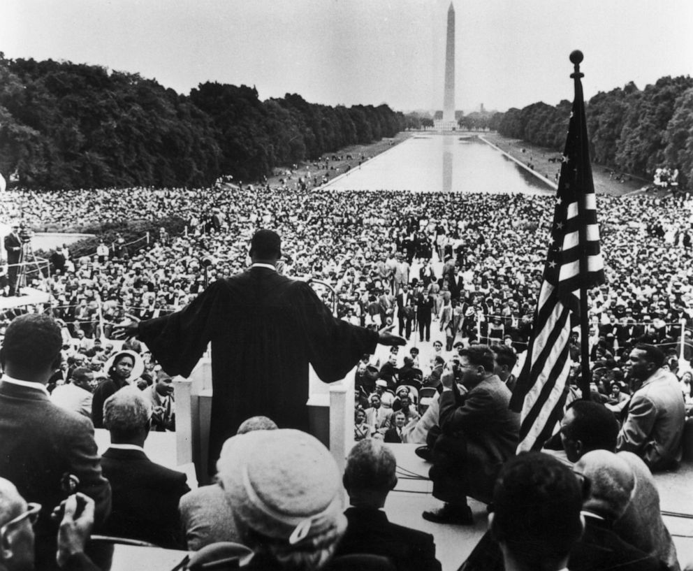 PHOTO: Back view of American civil rights leader and Baptist minister Martin Luther King, Jr., dressed in black robes and holding out his hands towards the thousands of people who have gathered to hear him speak in Washington, MAy 17, 1957.