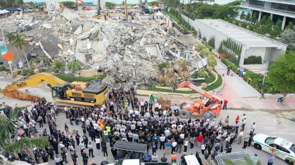 PHOTO: In this still image taken from drone footage posted on social media, search and rescue teams stand during a moment of silence in front of the rubble of the collapsed Champlain Towers South condominium in Surfside, Florida, on  July 7, 2021.