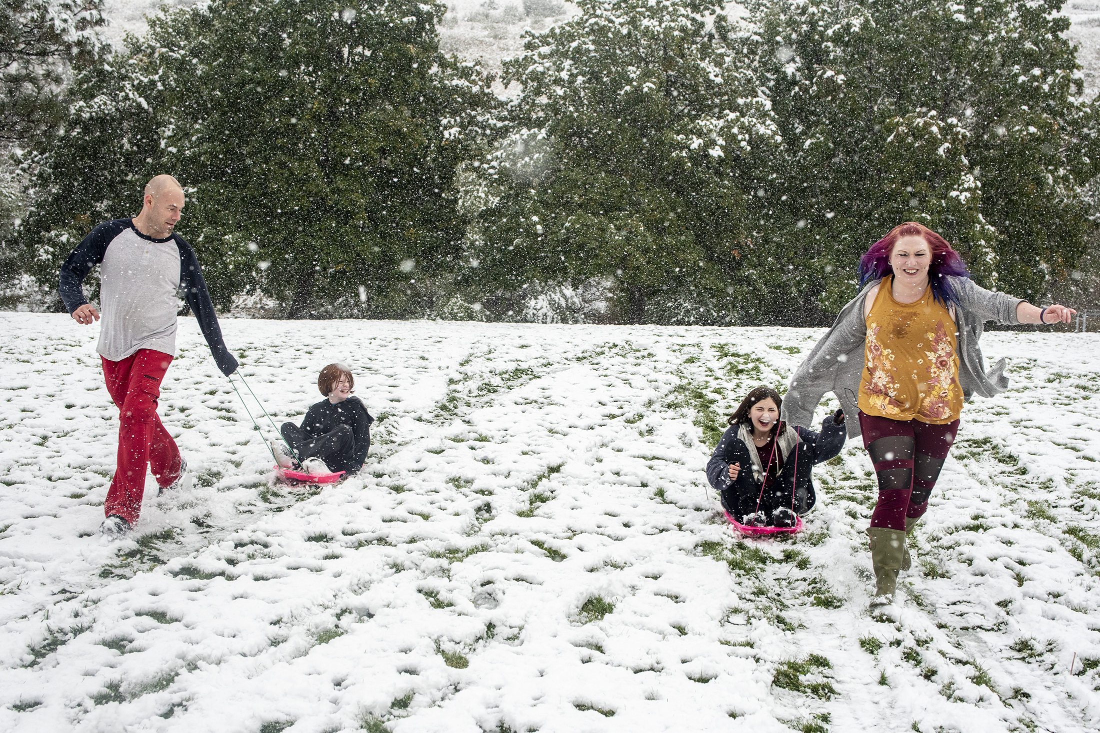 PHOTO: From left, Tommy Little, Cody Little, Kyndra Neal and Tanya Little sled down a hill in Missoula, Mont., Sept. 29, 2019 after snow in an early winter storm.