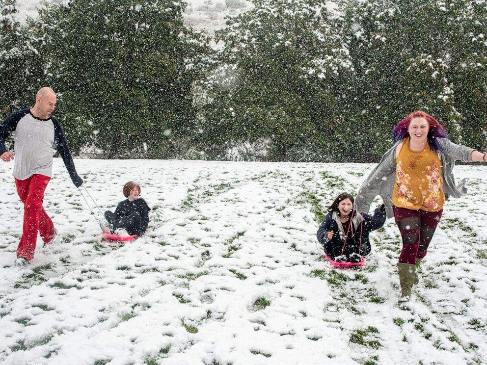 PHOTO: From left, Tommy Little, Cody Little, Kyndra Neal and Tanya Little sled down a hill in Missoula, Mont., Sept. 29, 2019 after snow in an early winter storm.