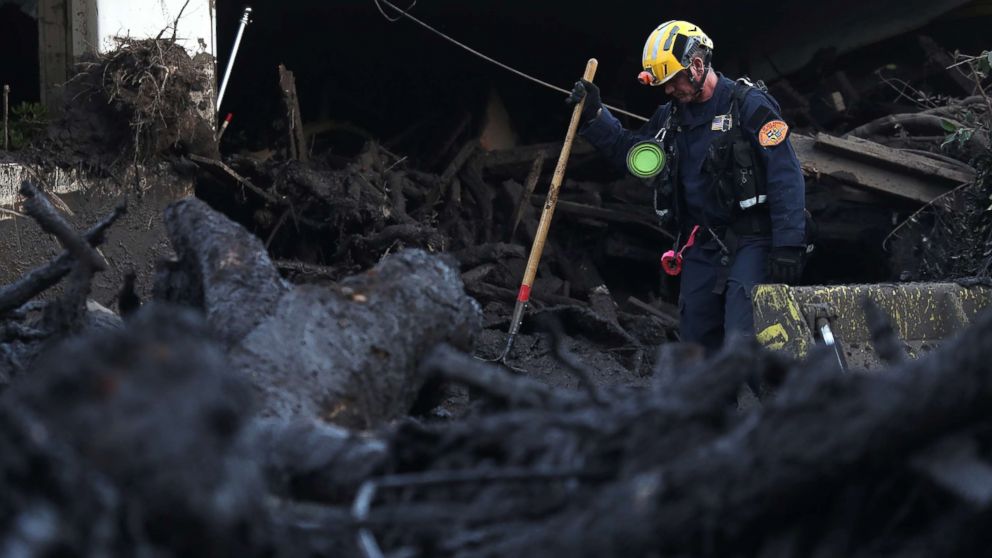 A Los Angeles County urban search and rescue worker searches a pile of debris for victims of a mudslide, Jan. 11, 2018 in Montecito, Calif.