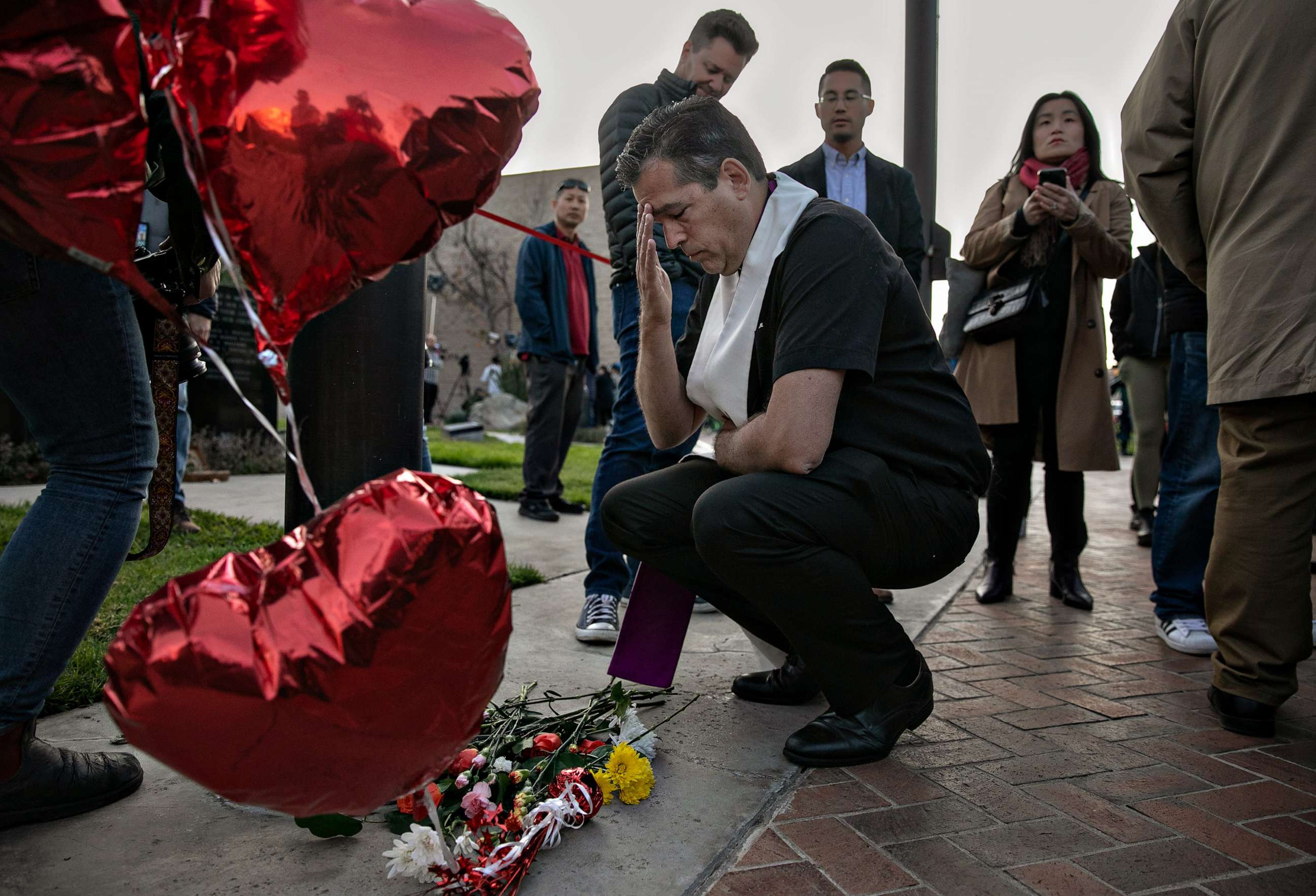 PHOTO: A faith leader says a prayer after placing flowers at a memorial for the people who were killed by a gunman at a ballroom dance studio, Jan. 22, 2023, in Monterey Park, Calif.