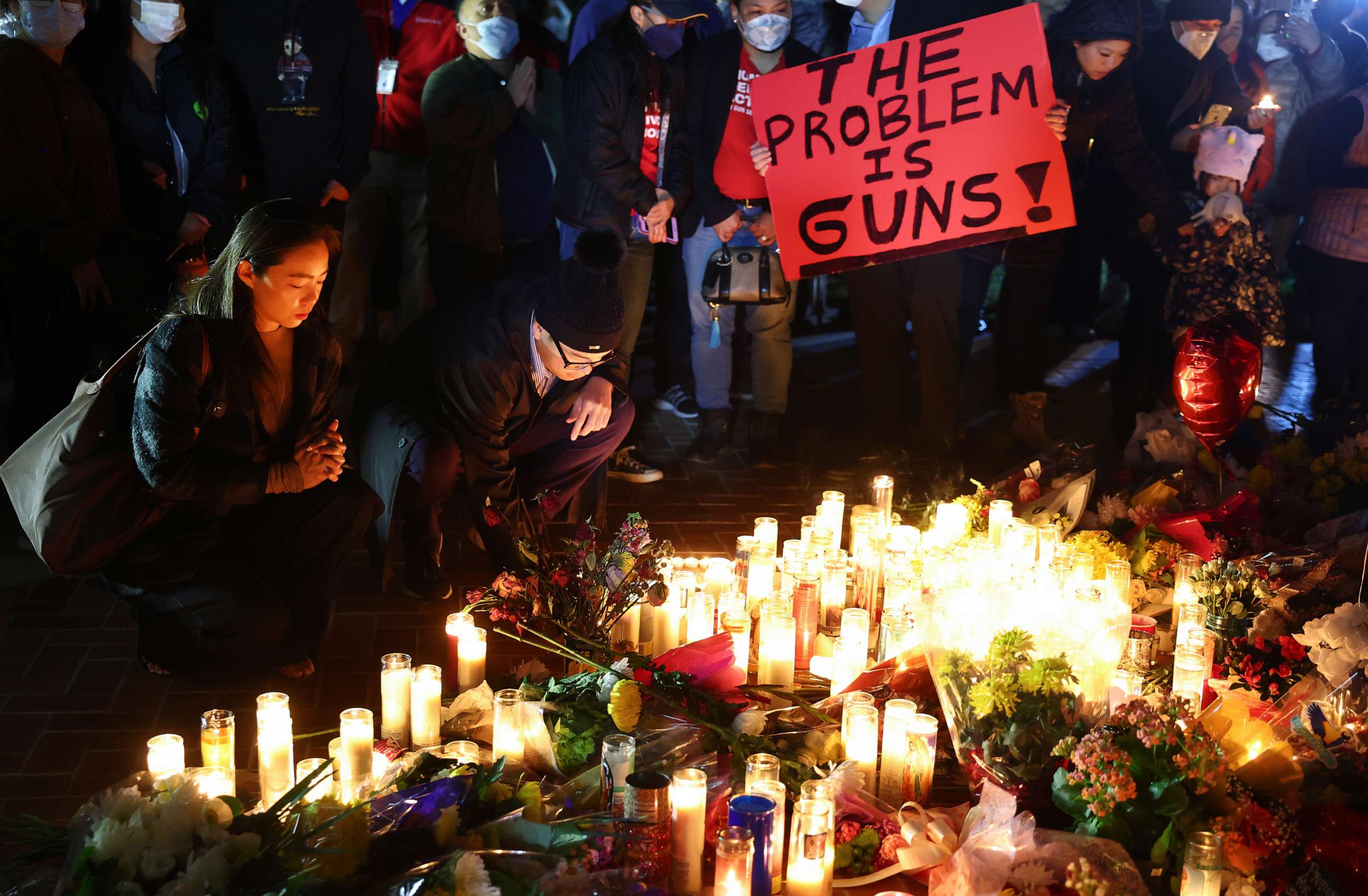 PHOTO: People attend a candlelight vigil for victims of a deadly mass shooting at a ballroom dance studio, as a person holds a sign reading "The Problem Is Guns!", on Jan. 24, 2023 in Monterey Park, Calif.