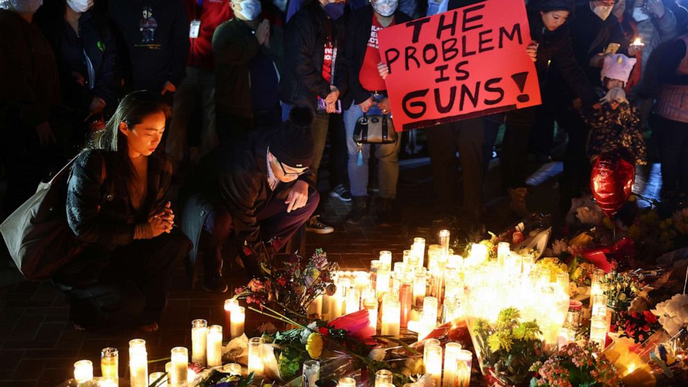 PHOTO: Les gens assistent à une veillée aux chandelles pour les victimes d'une fusillade de masse mortelle dans un studio de danse de salon, alors qu'une personne tient une pancarte lisant "Le problème, ce sont les armes !"le 24 janvier 2023 à Monterey Park, Californie.