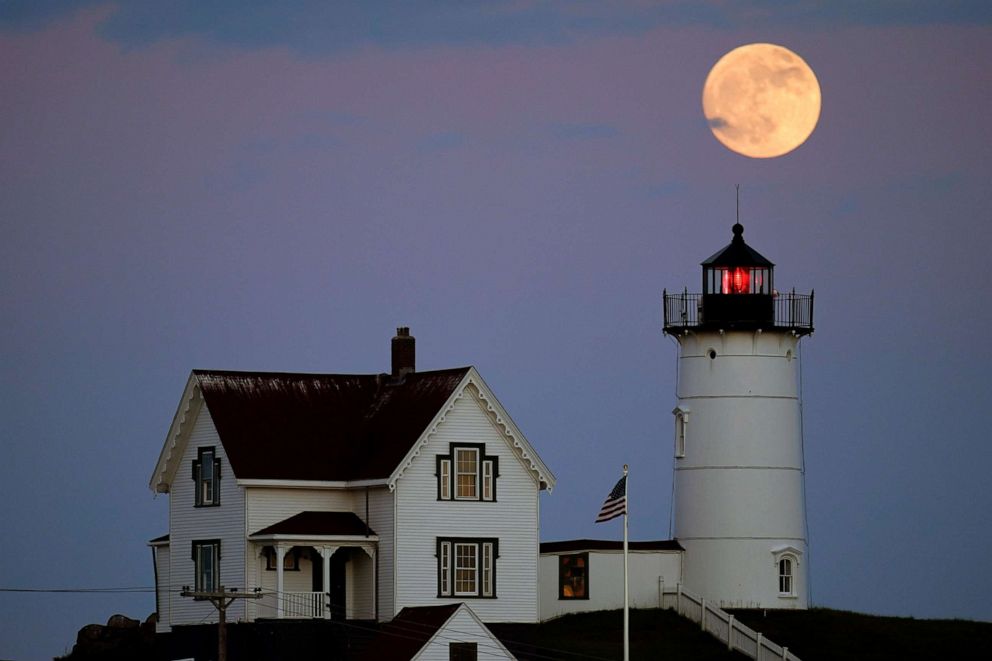 PHOTO: A moon is seen as it rises near the Nubble Light, June 13, 2022, in York, Maine.