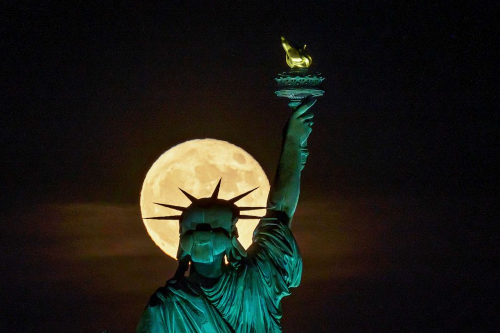 PHOTO: The moon rises in front of the Statue of Liberty in New York, June 14, 2022.
