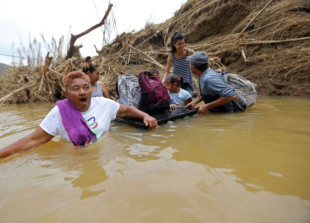 PHOTO: Marta Sostre Vazquez reacts as she starts to wade into the San Lorenzo Morovis river with her family, after the bridge was swept away by Hurricane Maria, in Morovis, Puerto Rico, Sept. 27, 2017.