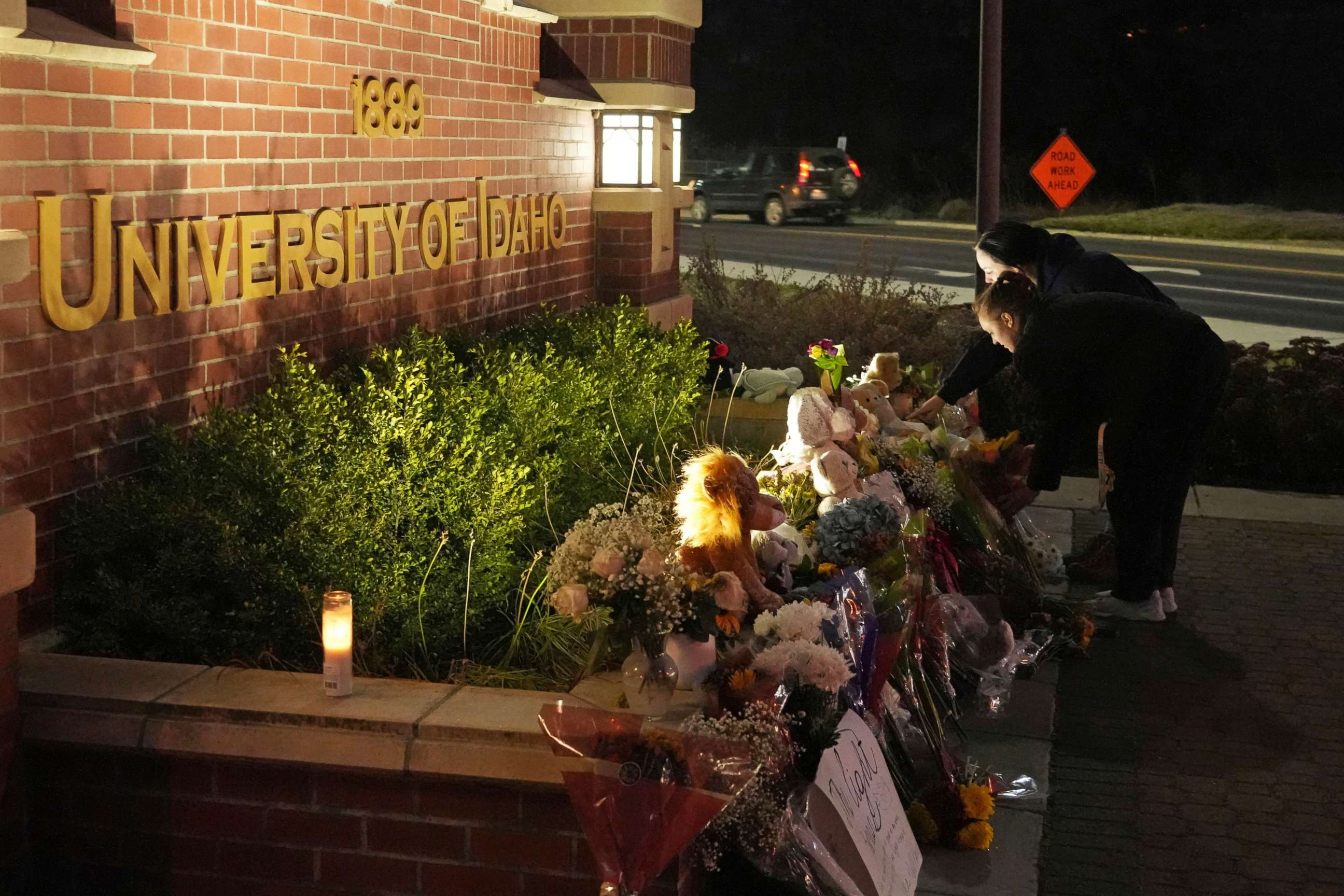 PHOTO: Two people place flowers at a growing memorial in front of a campus entrance sign for the University of Idaho, on Nov. 16, 2022, in Moscow, Idaho. 