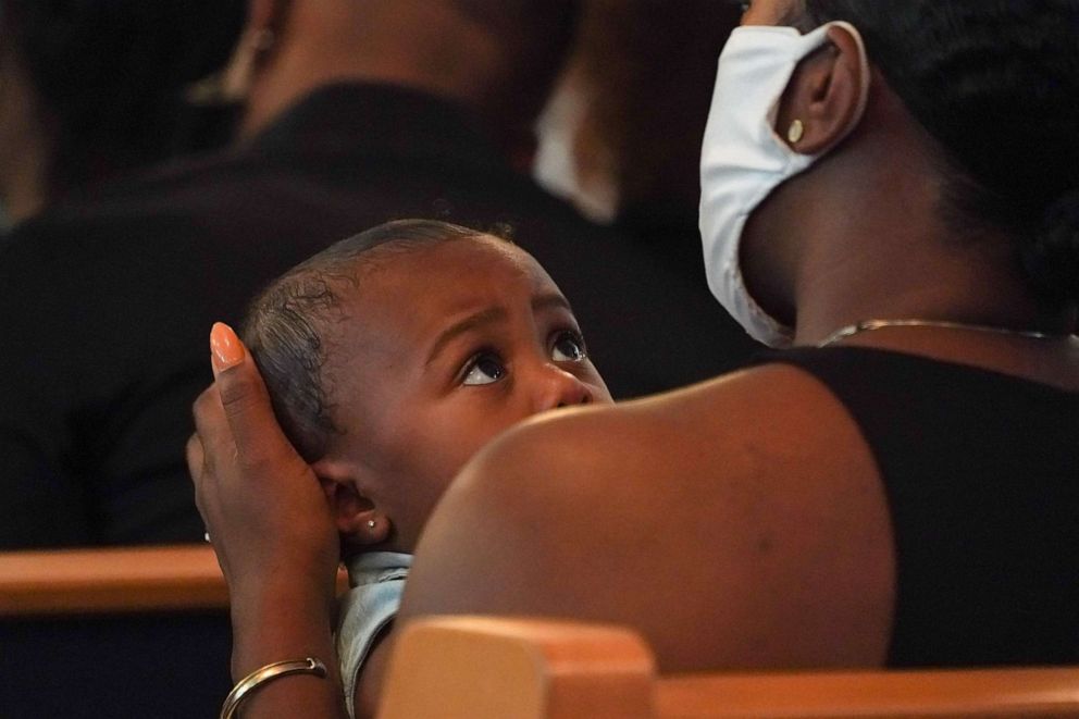 PHOTO: A child looks up at his mother during a double funeral service for Lola M. Simmons-Jones and her daughter Lashaye Antoinette Allen, who both died of COVID-19, at the Denley Drive Missionary Baptist Church in Dallas, Texas, on July 30, 2020.