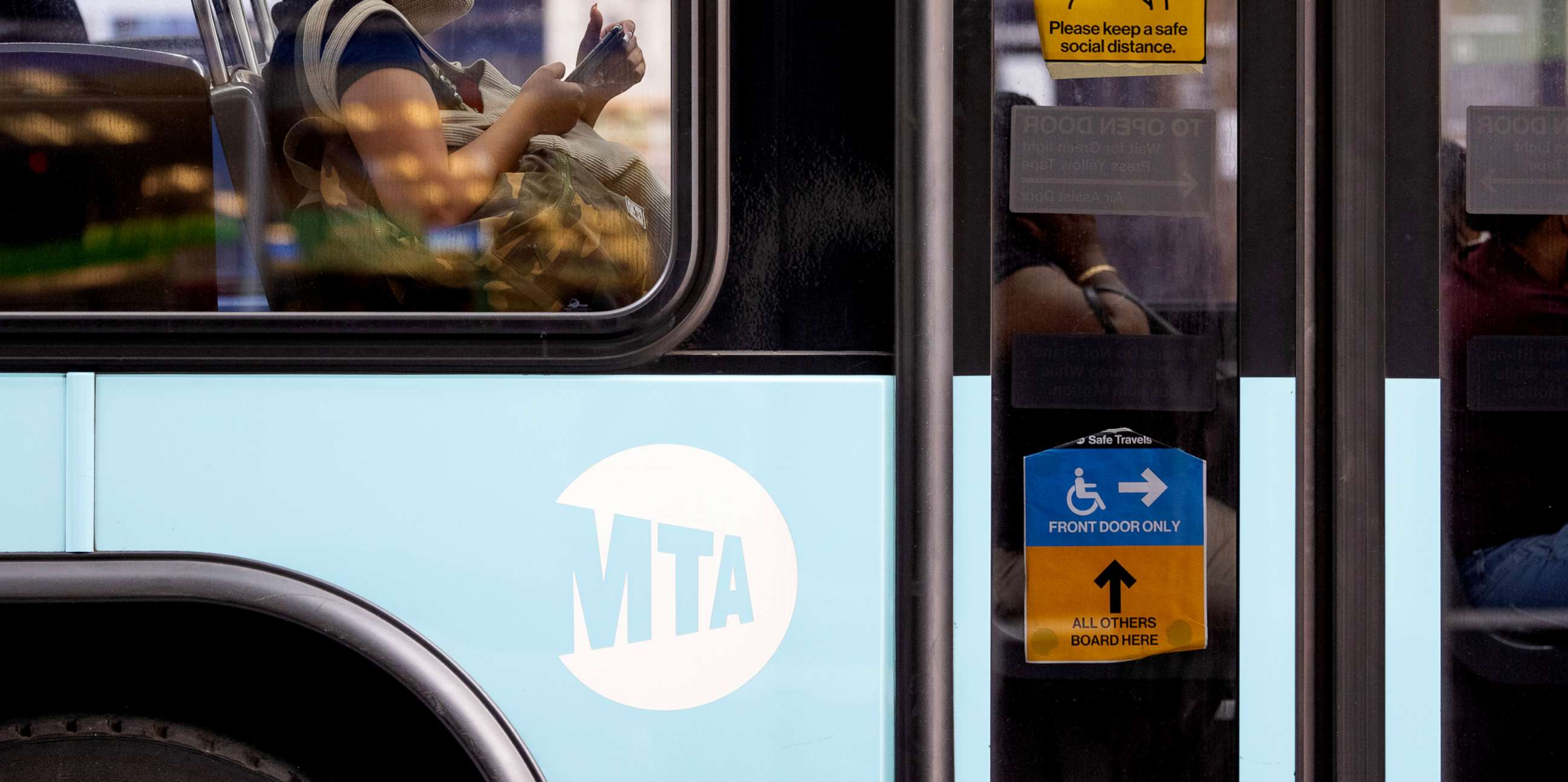 PHOTO: A woman wearing a mask is seen sitting inside a bus near a face coverings required sign as the city continues Phase 4 of re-opening following restrictions imposed to slow the spread of coronavirus, July 30, 2020, in New York.