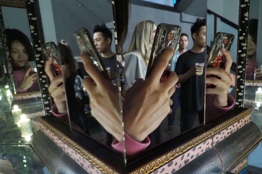 PHOTO: The hand of a visitor taking a photo with a cell phone is reflected in mirrors at the Museum of Selfies, in Glendale, Calif., March 29, 2018.