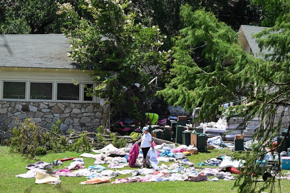 PHOTO: A woman sorts through clothing and campers belongings outside cabins at Camp Mystic along the Guadalupe River in Hunt, Texas, on July 8, 2025, after severe flash flooding over the July Fourth holiday weekend.