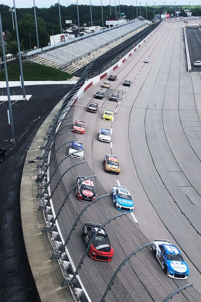 PHOTO: Drivers head through a turn in front of an empty grandstand during the NASCAR Cup Series auto race, May 17, 2020, in Darlington, South Carolina.