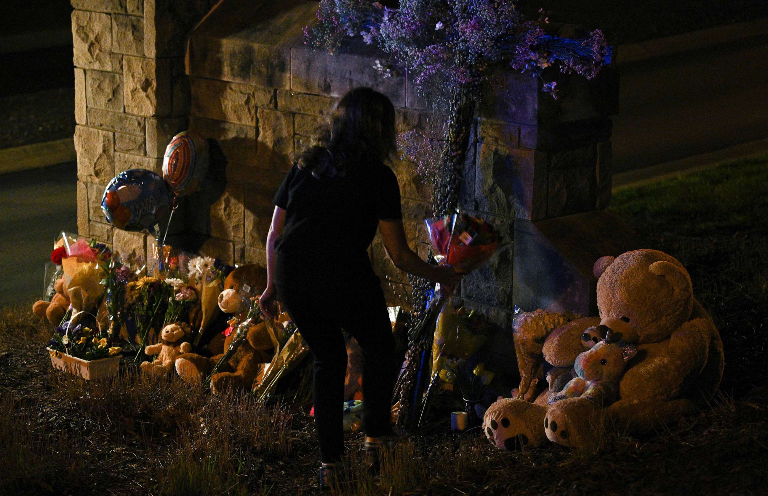 PHOTO: A woman places flowers at a makeshift memorial where balloons and Teddy bears are left on the outside the Covenant School building at the Covenant Presbyterian Church, in Nashville, Tenn., March 27, 2023.